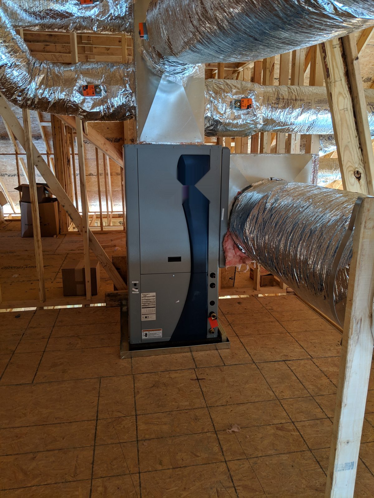 Geothermal heat pump installed in a home attic, connected to insulated ductwork