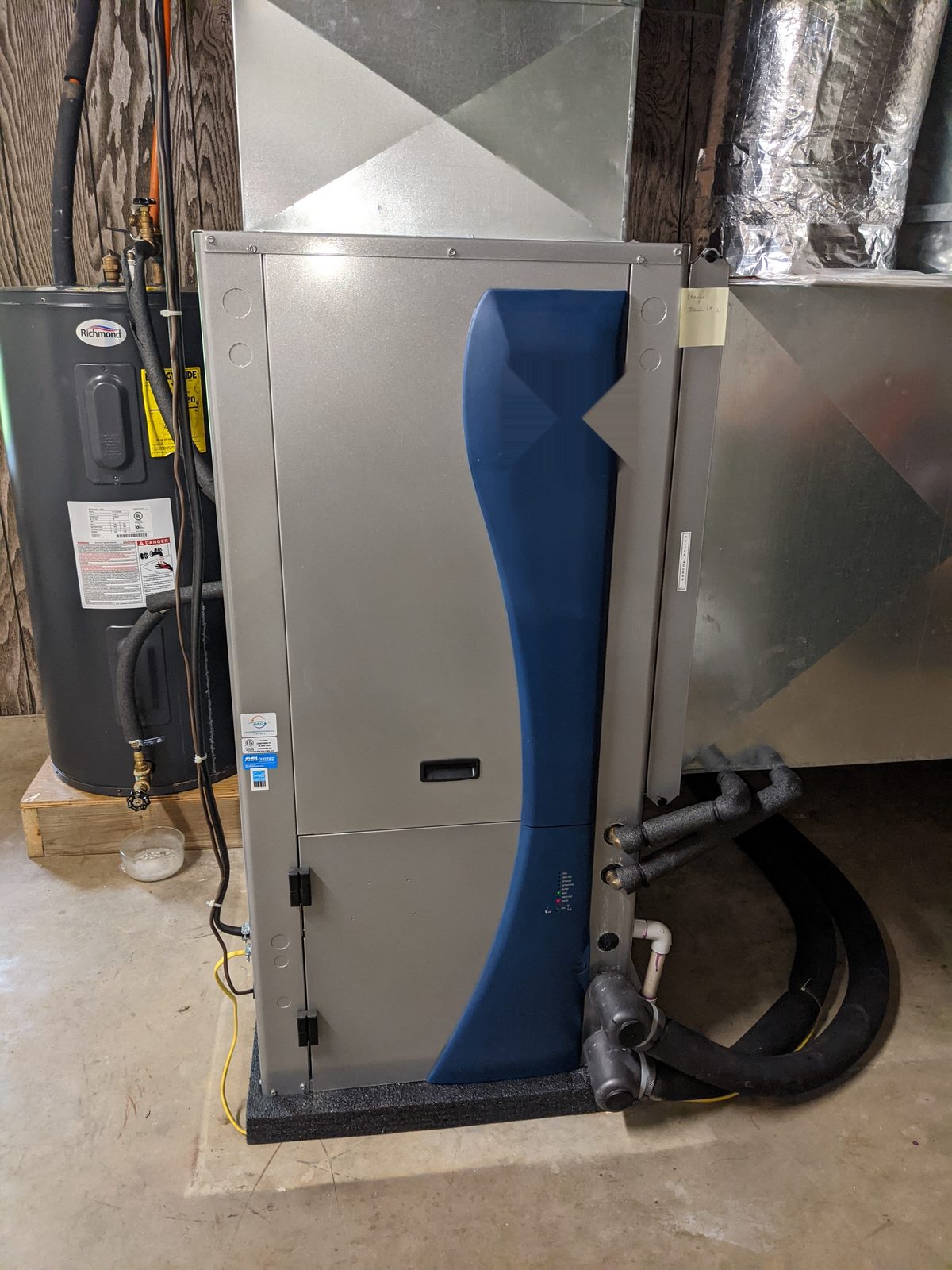 Geothermal heat pump installed in a utility closet beside a water heater