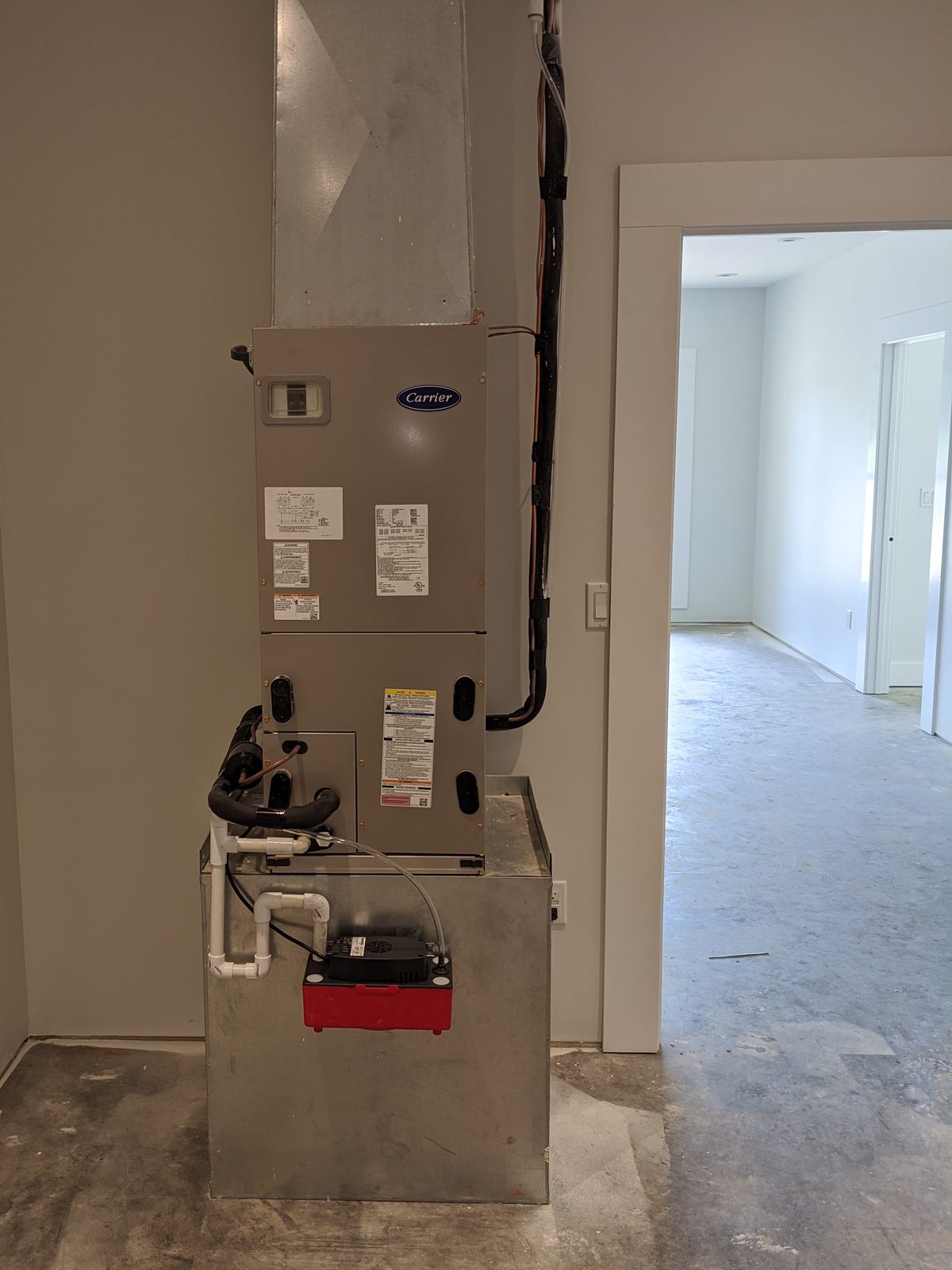 Carrier Infinity fan coil installed in a mechanical closet during new construction, with sealed return plenum and condensate pump
