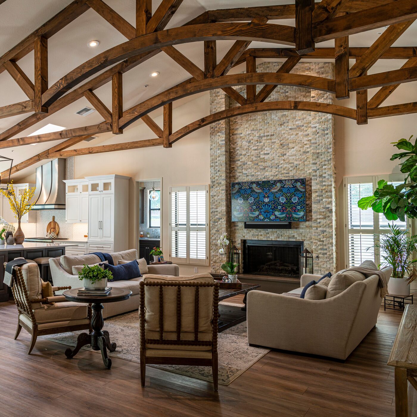 Open great room with vaulted timber-truss ceiling, stone fireplace and adjoining kitchen