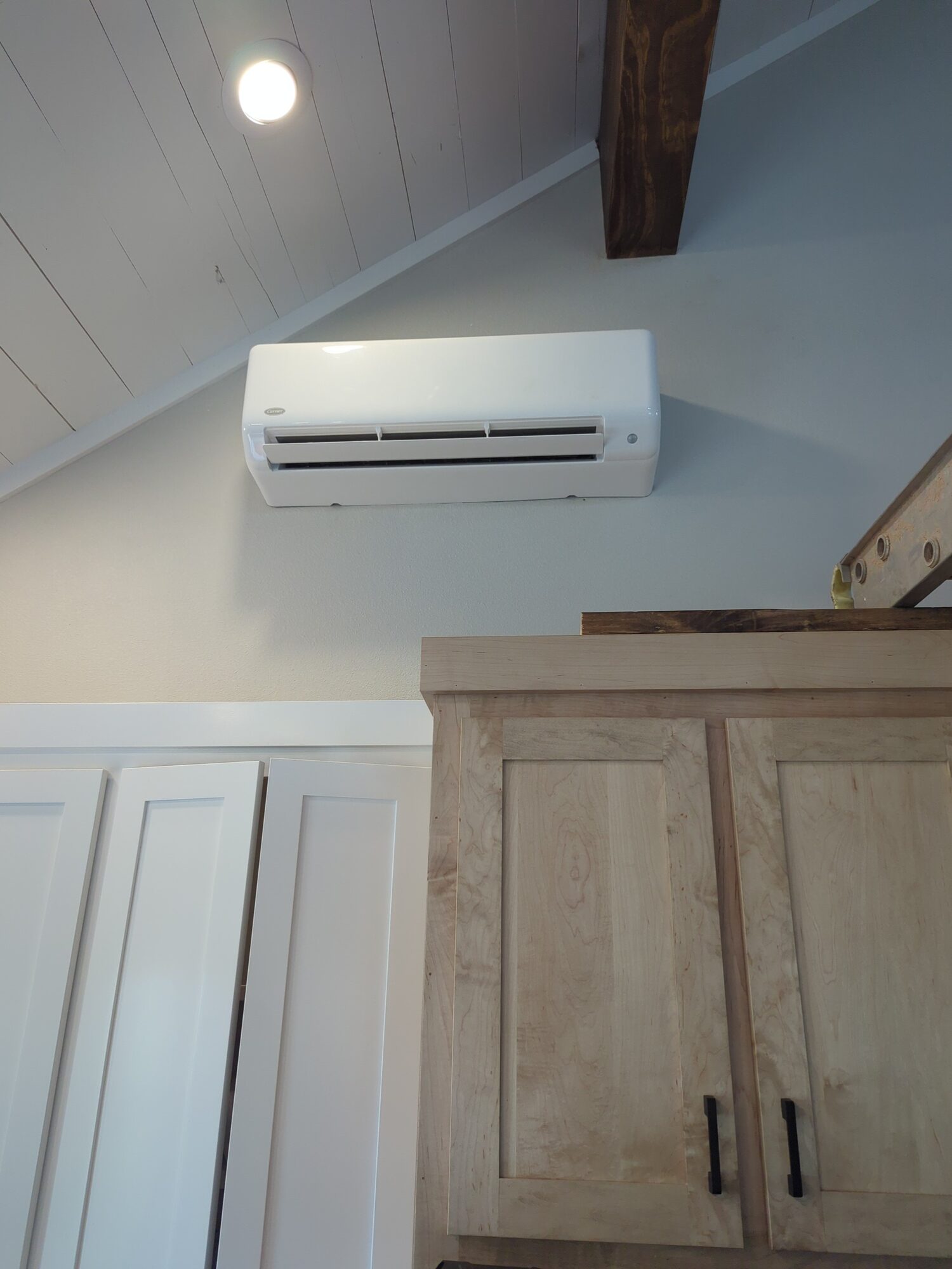 Carrier ductless mini-split indoor unit on a vaulted shiplap ceiling wall above kitchen cabinets