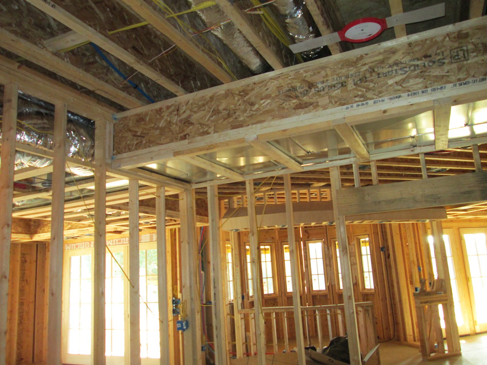 Sealed sheet metal ductwork and plenum run through open ceiling framing in a house under construction