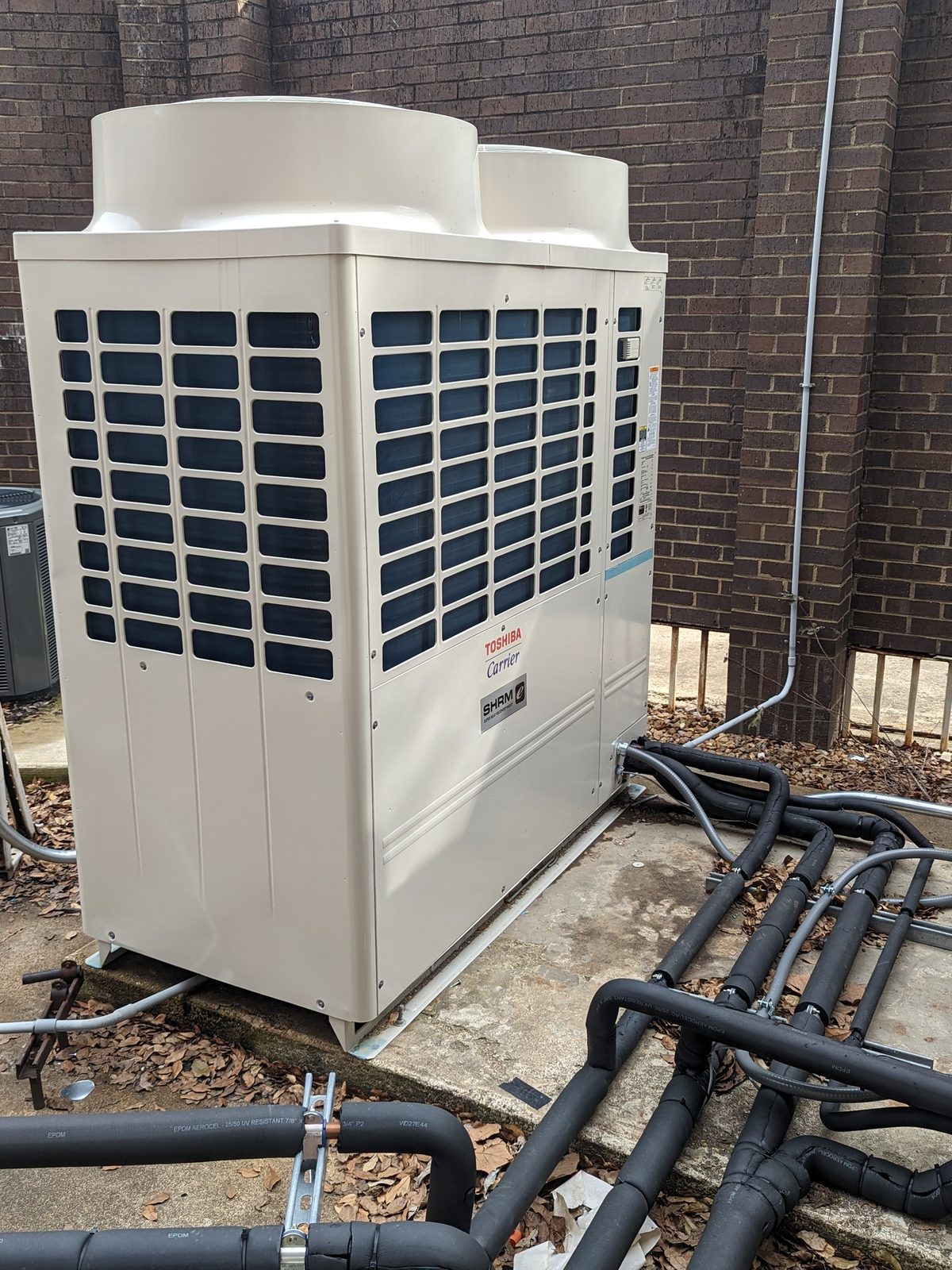 Toshiba-Carrier VRF condensing unit installed beside a commercial brick building