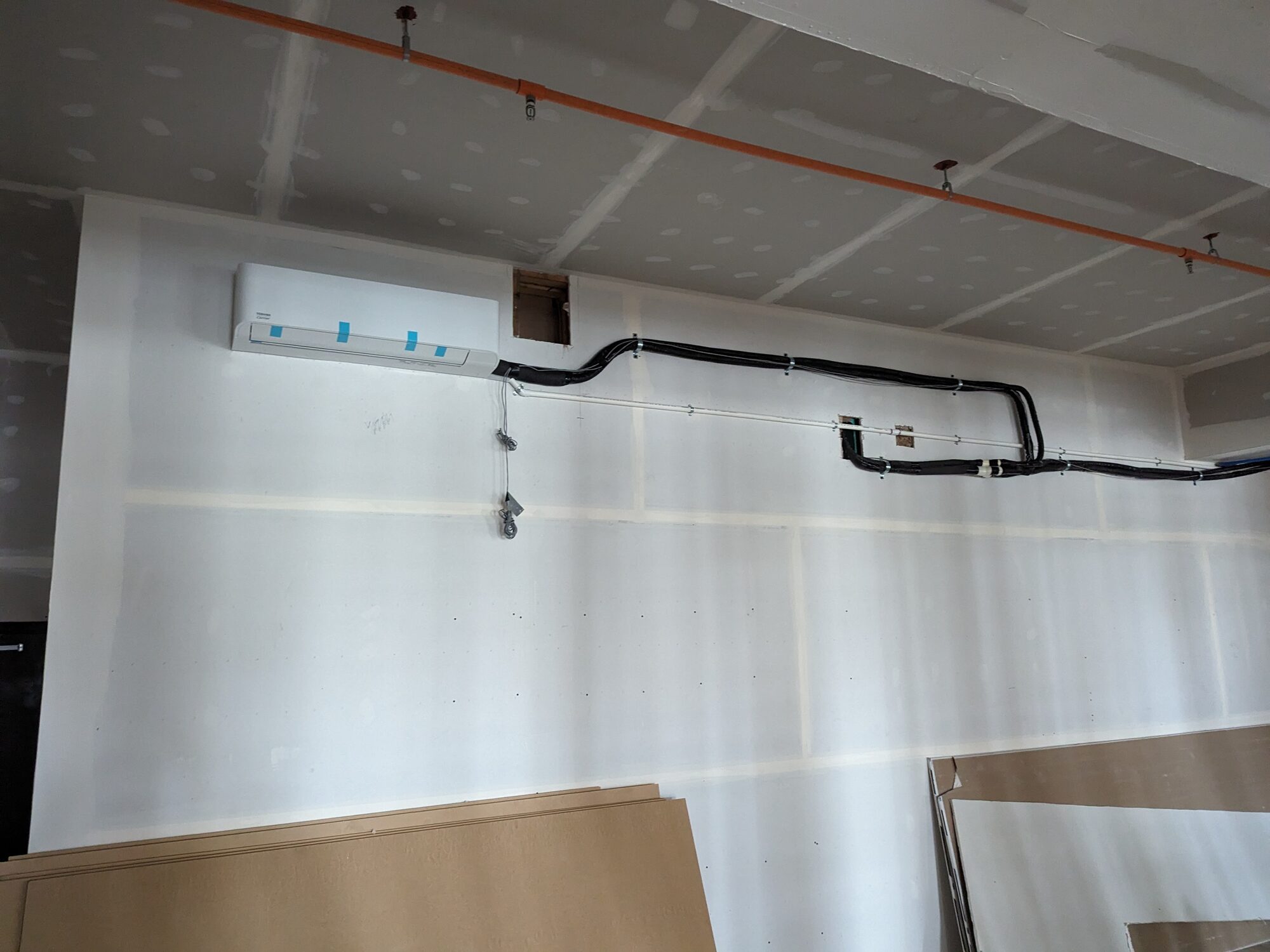 Toshiba-Carrier ductless indoor unit installed in a commercial build-out, refrigerant lines routed along the ceiling